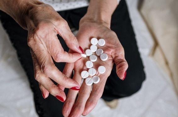 elderly woman's hands holding pills - Medication Mismanagement concept image