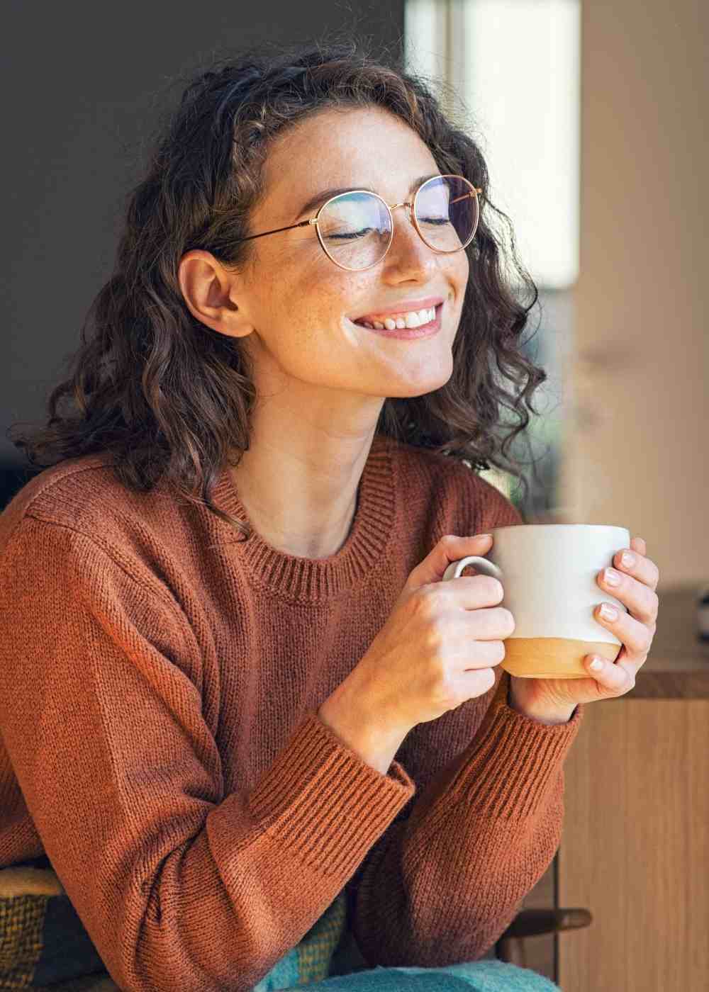 positive-thinking-cbt-recovery-wellbeing Woman smiling with a mug while finding calm through Cognitive Behavioral Therapy for addiction recovery.