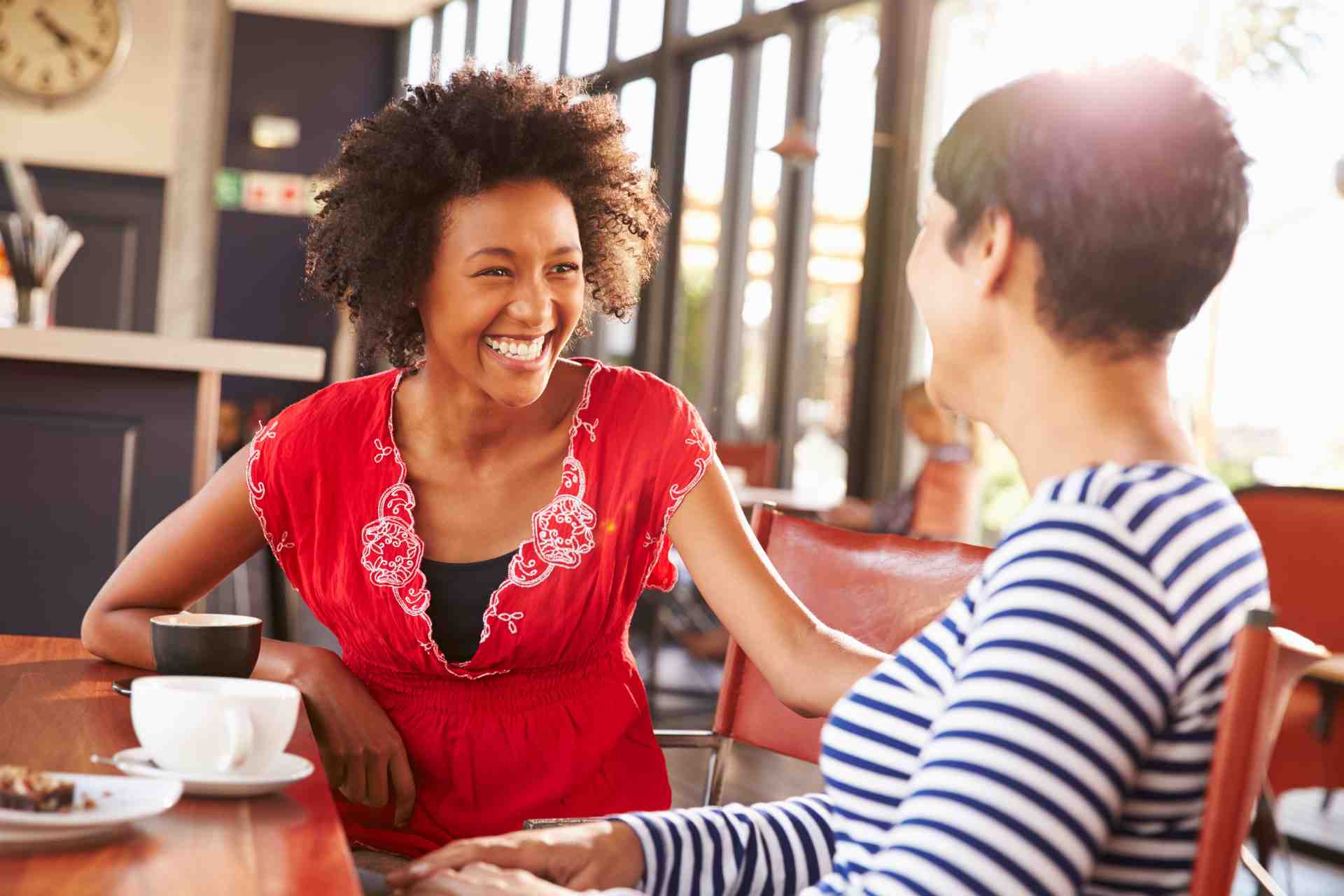 rehab-support-meeting Two women having a warm supportive conversation at a table about treatment and recovery