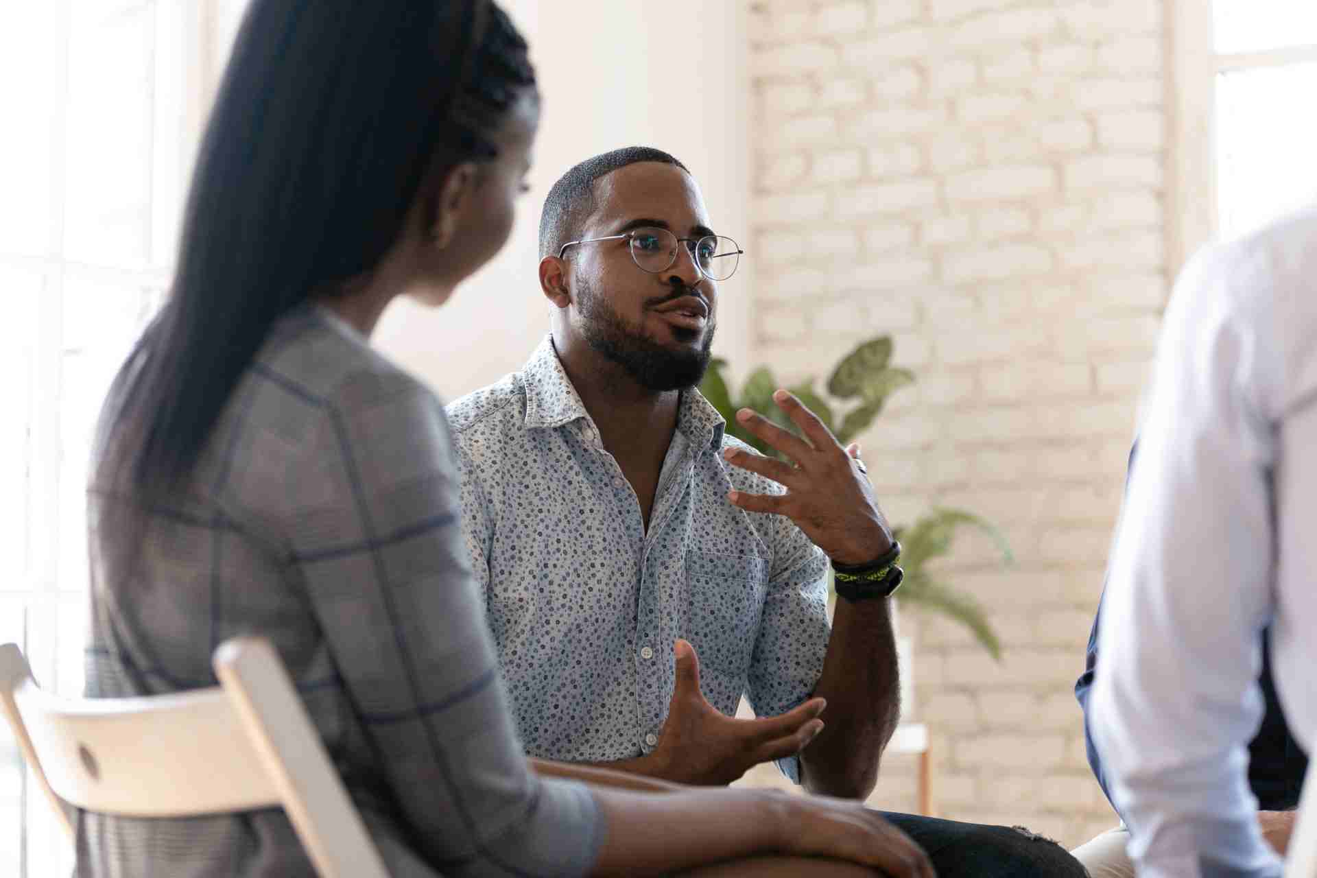 motivational-therapy-group-discussion Man speaking during motivational therapy group discussion for addiction recovery