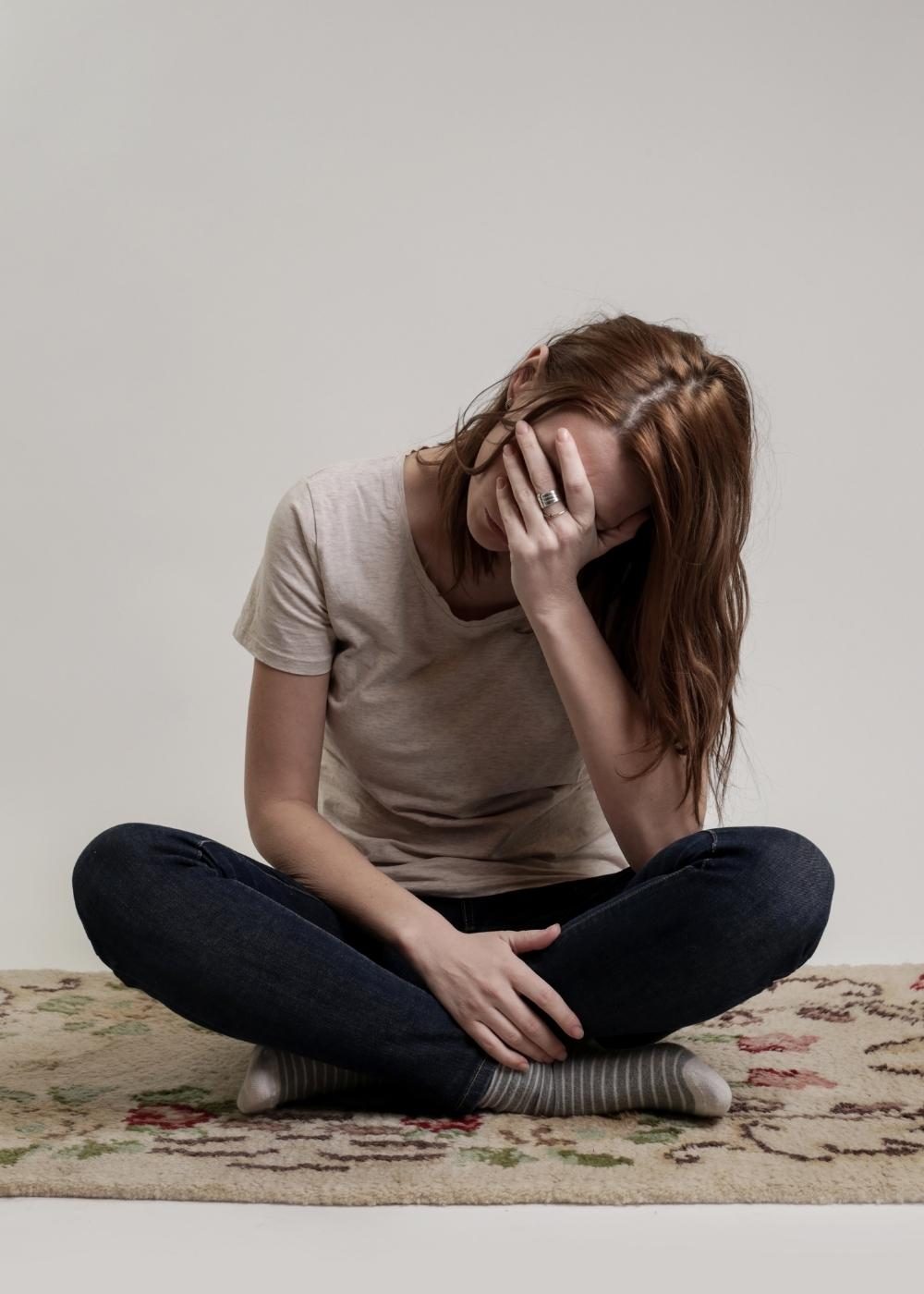 depression-recovery-support-treatment Woman sitting alone with her head in her hand, representing the emotional challenges of depression and the importance of seeking professional mental health treatment.