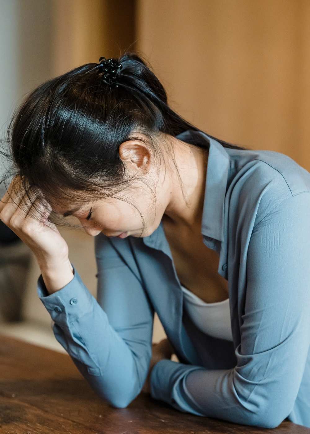 dual-diagnosis-depression-treatment Woman experiencing symptoms of depression with her head resting on her hand, representing the challenges of dual diagnosis involving depression and substance use disorders.