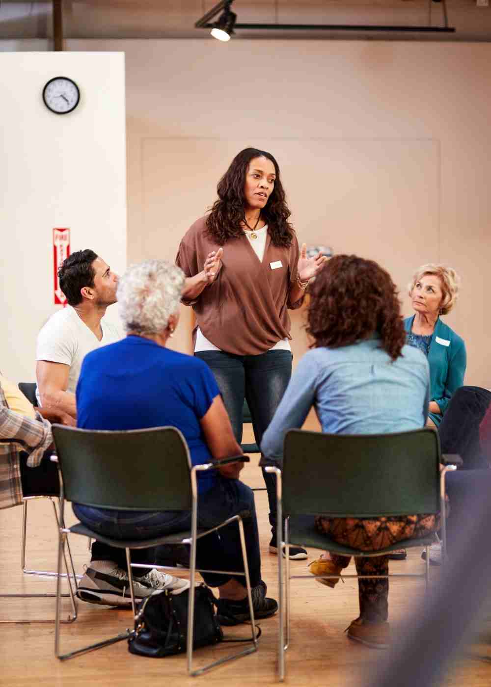 Participants celebrating a group member's progress during a group therapy session for addiction recovery.